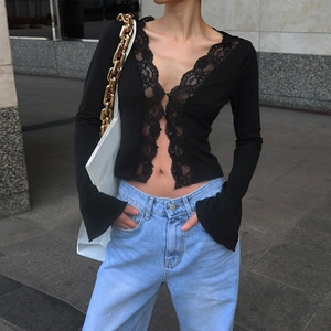 Detailed view of black long-sleeve top with elegant lace patchwork and deep V-neckline