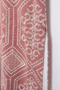 Close-up of white geometric embroidery on dusty pink cotton fabric with side slit detail