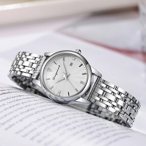 Vue macro d'une montre à quartz argentée avec index strass et guichet de date sur un livre