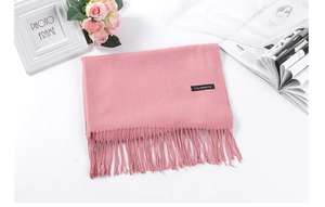 Detail shot of soft pink cashmere-style scarf with fringe on a white decorative background