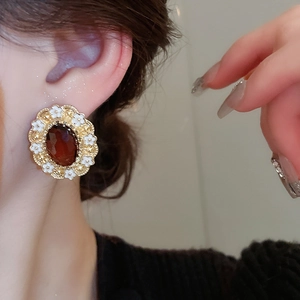 Detail of vintage oval red gemstone earrings with gold floral lace trim on a model