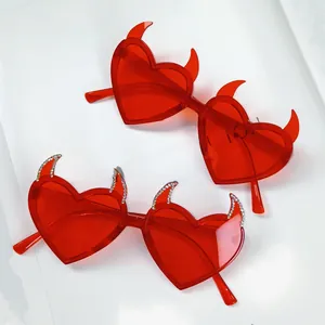 Close-up of red heart sunglasses featuring devil horns and sparkling rhinestone details
