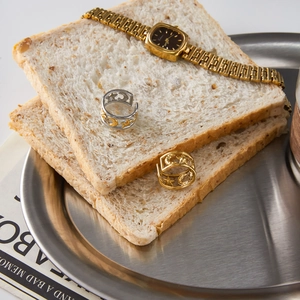 Star and moon engraved rings and gold watch displayed on a slice of toasted bread