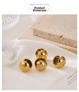 Close-up of gold ball stud earrings featuring one smooth pair and one heart-shaped zircon pair