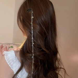 Vue détaillée d'une chaîne de cheveux argentée avec des étoiles sur longs cheveux bouclés