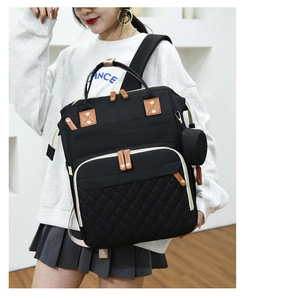 Front view of black diaper backpack with quilted detail and hanging pacifier pouch