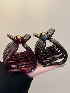 Detail view of large acrylic hair claws in deep purple and dark coffee tones with gold springs