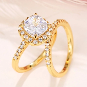 Detail of gold plated ring set featuring square halo cut crystal on pink feather
