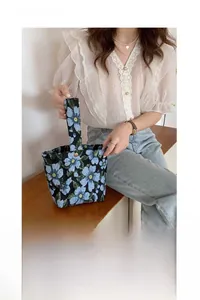 Detailed shot of vintage blue floral jacquard underarm bag being held by a model