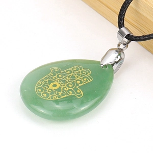 Macro view of green jade teardrop pendant with golden Hamsa Hand engraving on black cord