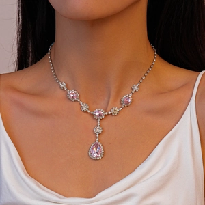 Gros plan d'un collier de mariée avec pierre rose en goutte d'eau sur du tissu de soie