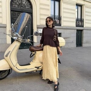 Elegant pleated pale yellow maxi skirt paired with a brown blouse in a retro street setting