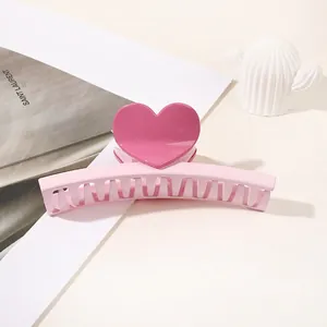 Detailed view of sweet pink heart-shaped hair claw clip on a minimalist white desk