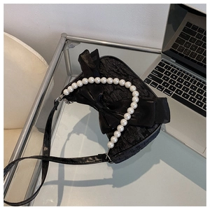 Detail of black jacquard handbag with oversized bow and elegant pearl handle strap