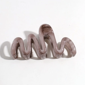Detail view of wavy hair claw clip with translucent brown marble patterns and glossy finish