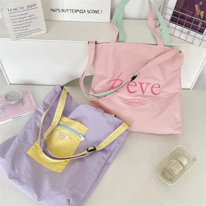 Detail of macaron-colored nylon tote bags with embroidery and adjustable straps
