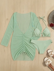 Three-piece pale green bikini set with mesh drawstring cover-up dress on a wooden surface