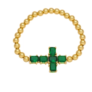 Elegant beaded gold bracelet featuring emerald green gemstones and a cross charm detail