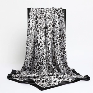 Elegant satin leopard print square scarf in black and white hanging on a display stand