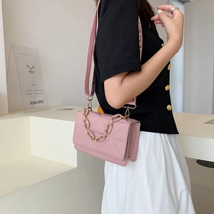 Detail view of pink quilted crossbody bag with chunky chain strap on a female model