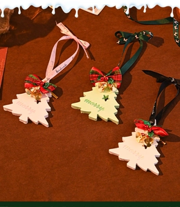 Detail of wooden Christmas tree pendants with checkered bows, bells and handmade straps