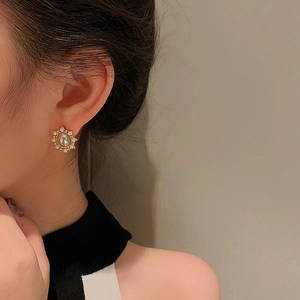 Detailed close-up of retro gold floral stud earrings with oval moonstone and crystals