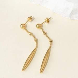 Detail of gold-plated stainless steel tassel earrings with round studs and drop cones