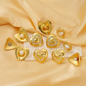 Close-up of gold heart and triangle earrings with pearls on champagne silk fabric