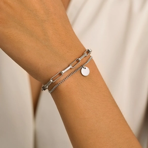 Detail of silver double-layered bracelet with paperclip chain and round pendant on wrist