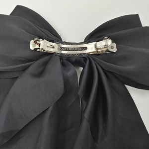 Close-up of the silver metal spring clip and satin texture on the large vintage bow