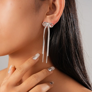 Detail of 18K gold plated bow earrings with long tassel fringes on a female model