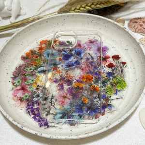 Detail of multi-colored floral stickers on a clear phone case displayed on ceramic tray