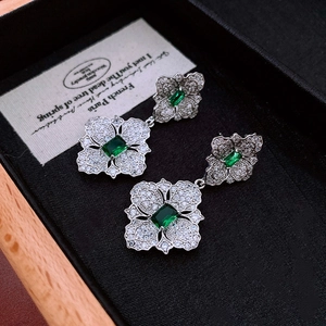 Detail of vintage flower earring featuring a green emerald-cut zircon in silver setting