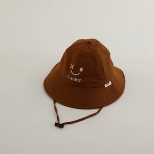 Close-up of caramel sun hat featuring Lucky smiley embroidery and windproof cord