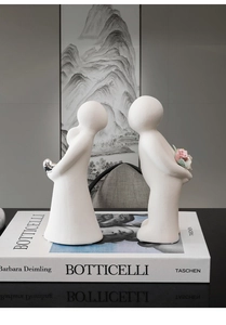 Detailed macro view of white ceramic couple figures with a pink flower and silver heart charm