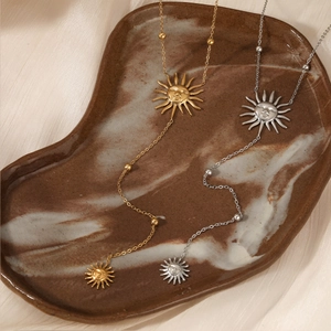 Elegant gold and silver stainless steel sun face pendant necklace set on ceramic plate