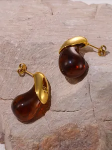 Detailed macro view of the irregular amber resin earrings and golden hardware on stone