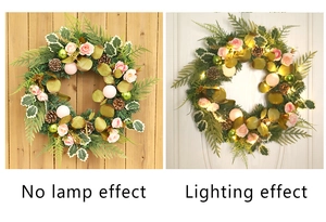 Detail of Christmas wreath featuring pink roses, pine cones and warm LED light effects