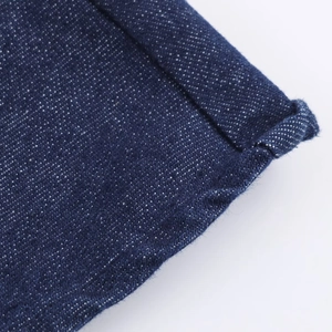 Macro de l'ourlet de robe en jean bleu foncé montrant la texture et les coutures