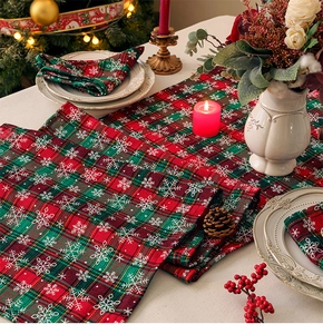 Close-up of red plaid Christmas table runner and napkin with snowflake patterns