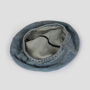 Close-up of blue denim beret showing metal buckle detail and inner lining structure
