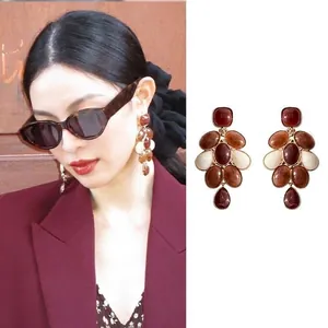 Détail de boucles d'oreilles plaquées or 18 carats avec pierres œil de tigre marron