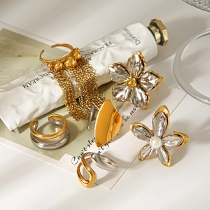 Detail of gold and silver tone rings with flower pearl earrings and metal tassels