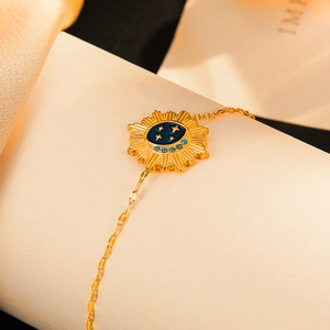 Gold star and moon charm bracelet with navy blue enamel sun pendant on a beige surface