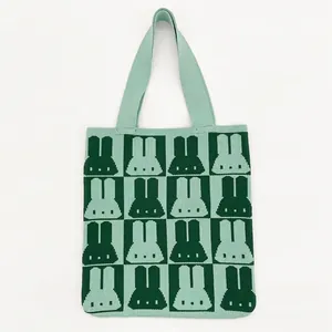 Close-up of green checkerboard knitted tote bag with cute cartoon rabbit pattern texture