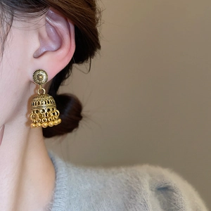 Detail of vintage gold-toned Jhumka bell earrings with hollow floral design and tassels
