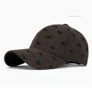 Close-up of brown textured baseball cap with embroidered black bow patterns