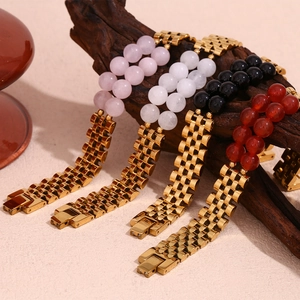 Détail du bracelet en métal doré 18K avec perles de pierre naturelle sur support bois