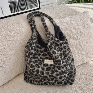 Detail of grey leopard faux fur tote bag showing plush texture on a cozy sofa