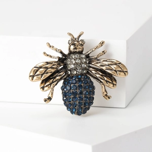 Detailed close-up of a vintage gold bee brooch with blue and clear rhinestones